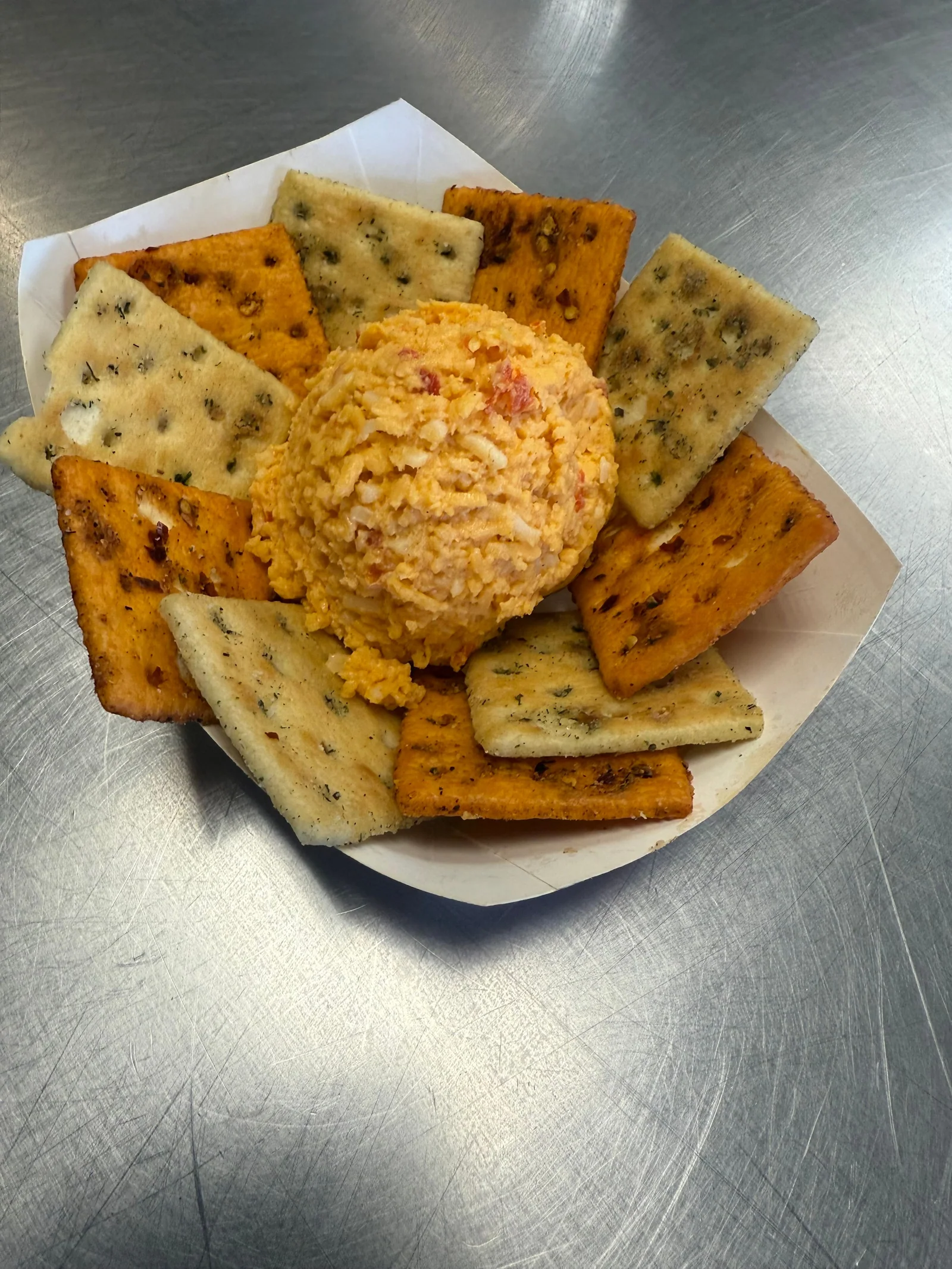A round cheese spread surrounded by crisp crackers on a white plate