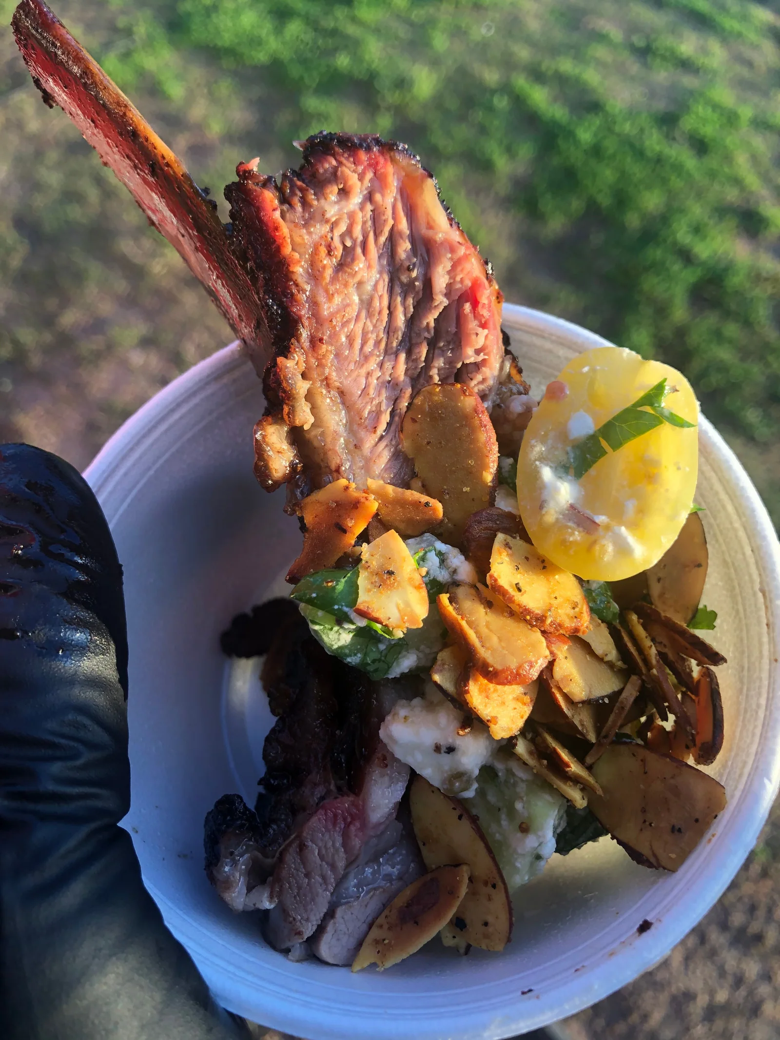A bone-in rib served upright with vegetables and a lemon wedge