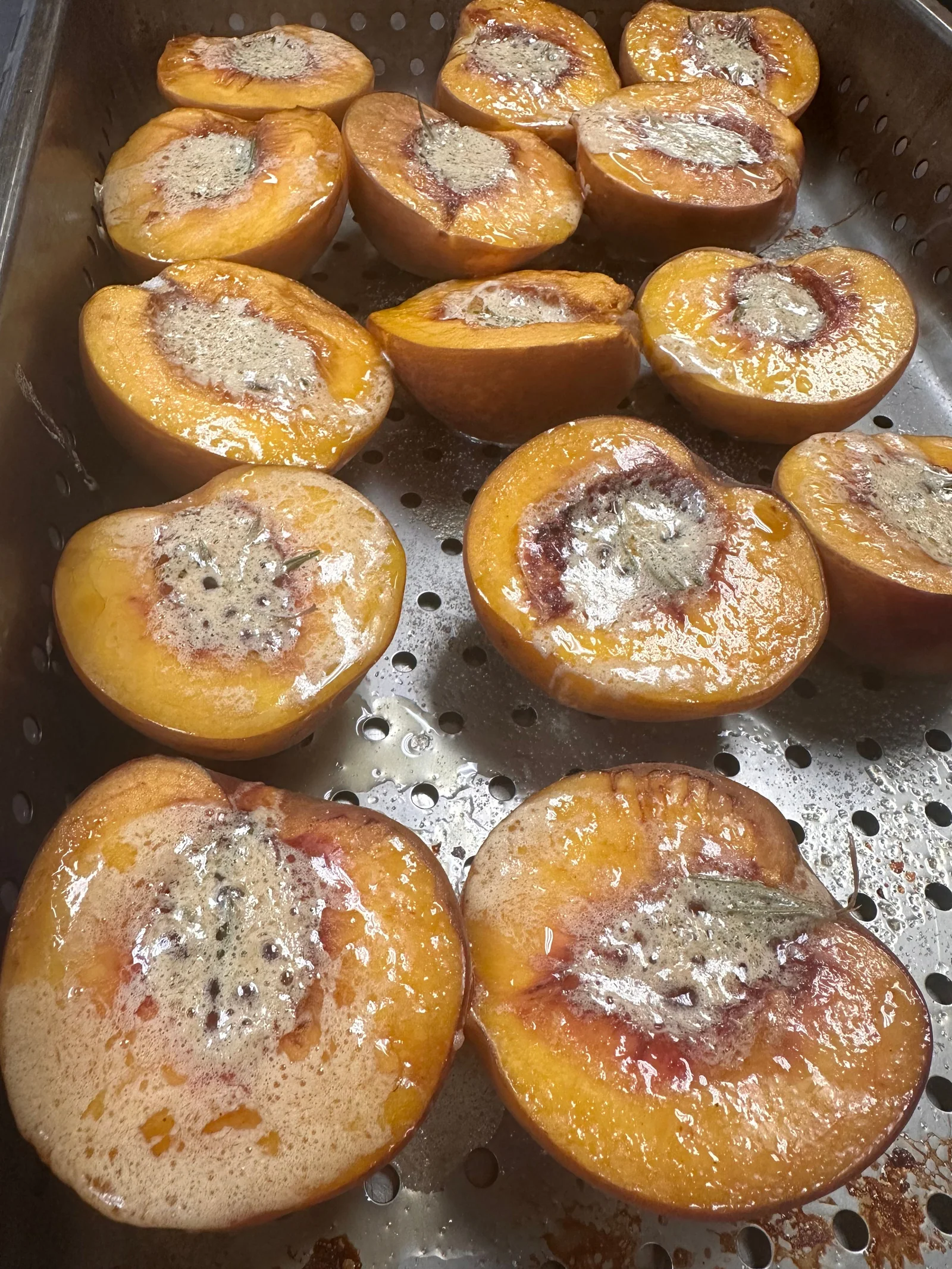 Halved peaches roasting on a sheet pan