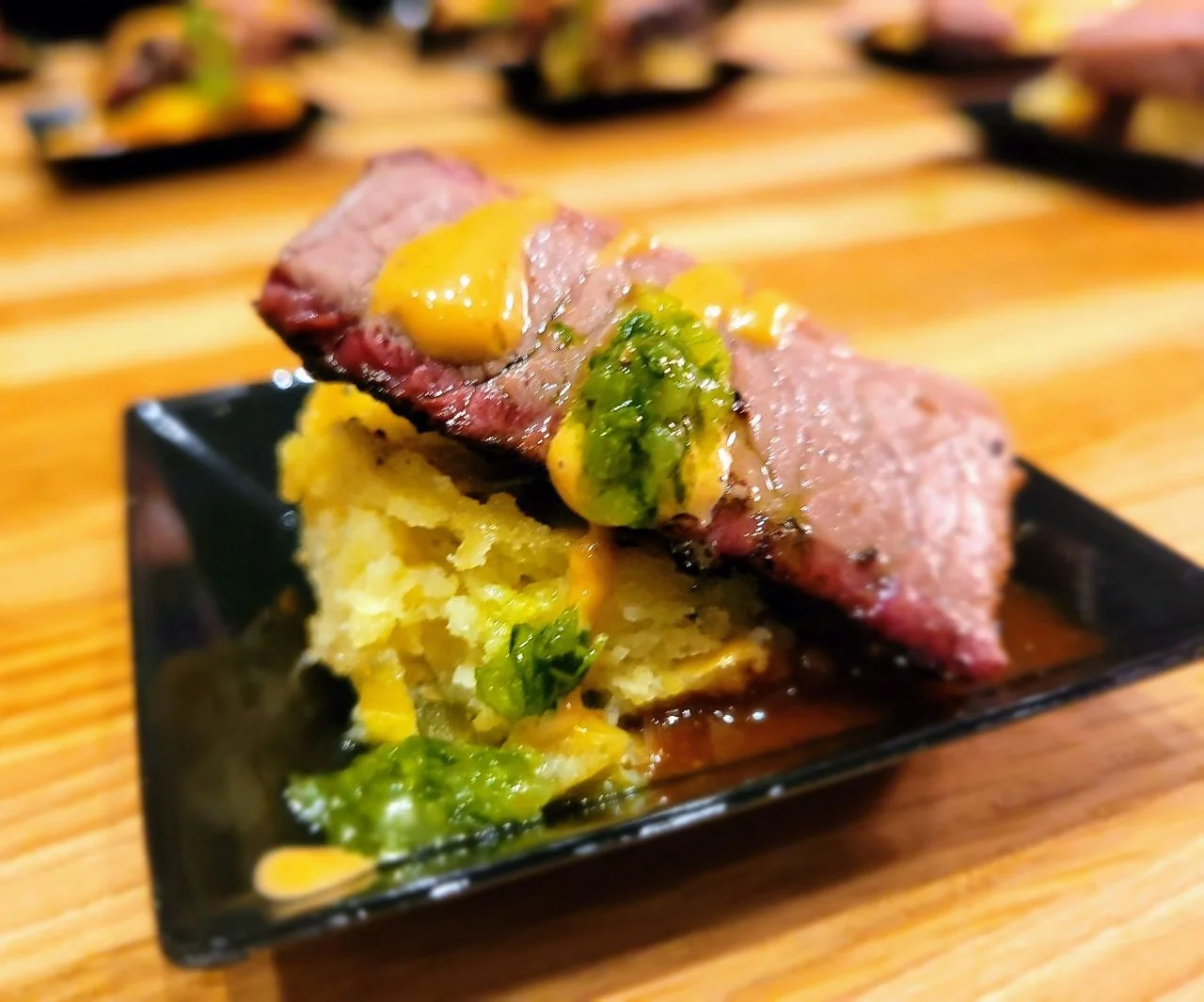 A small tasting plate topped with sliced meat and colorful garnish