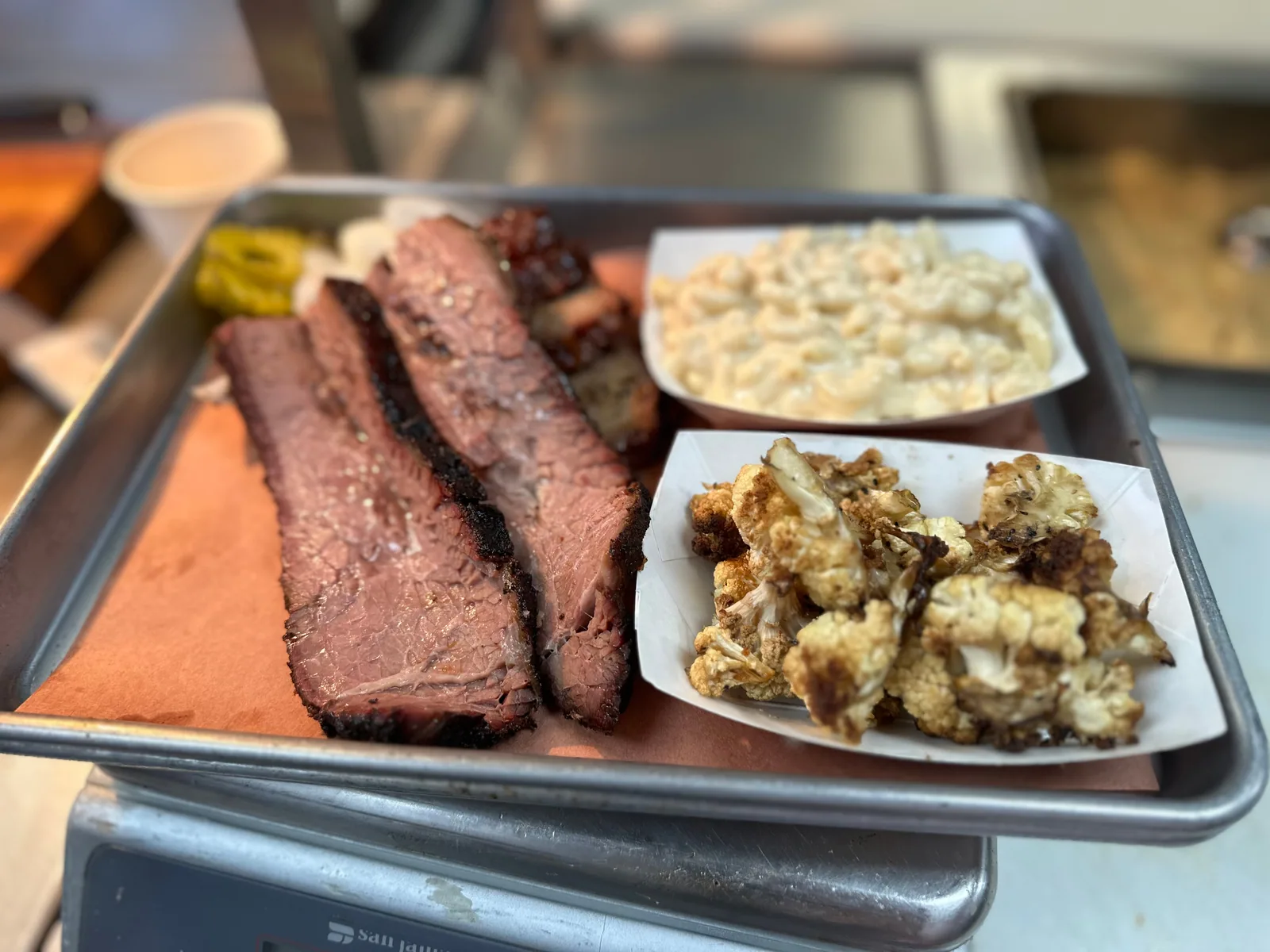 A tray of sliced brisket with roasted cauliflower and macaroni