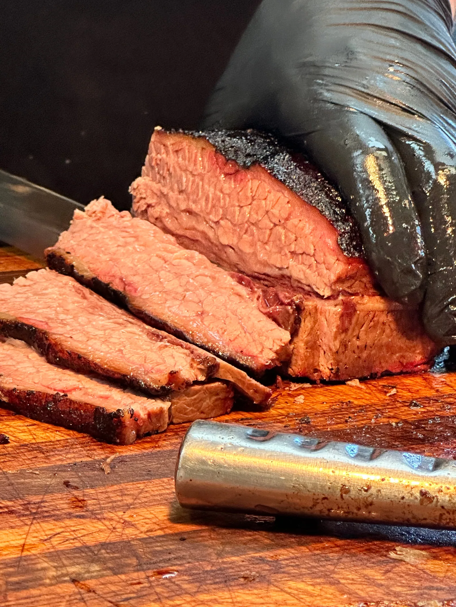 A cook slicing brisket on a wooden cutting board