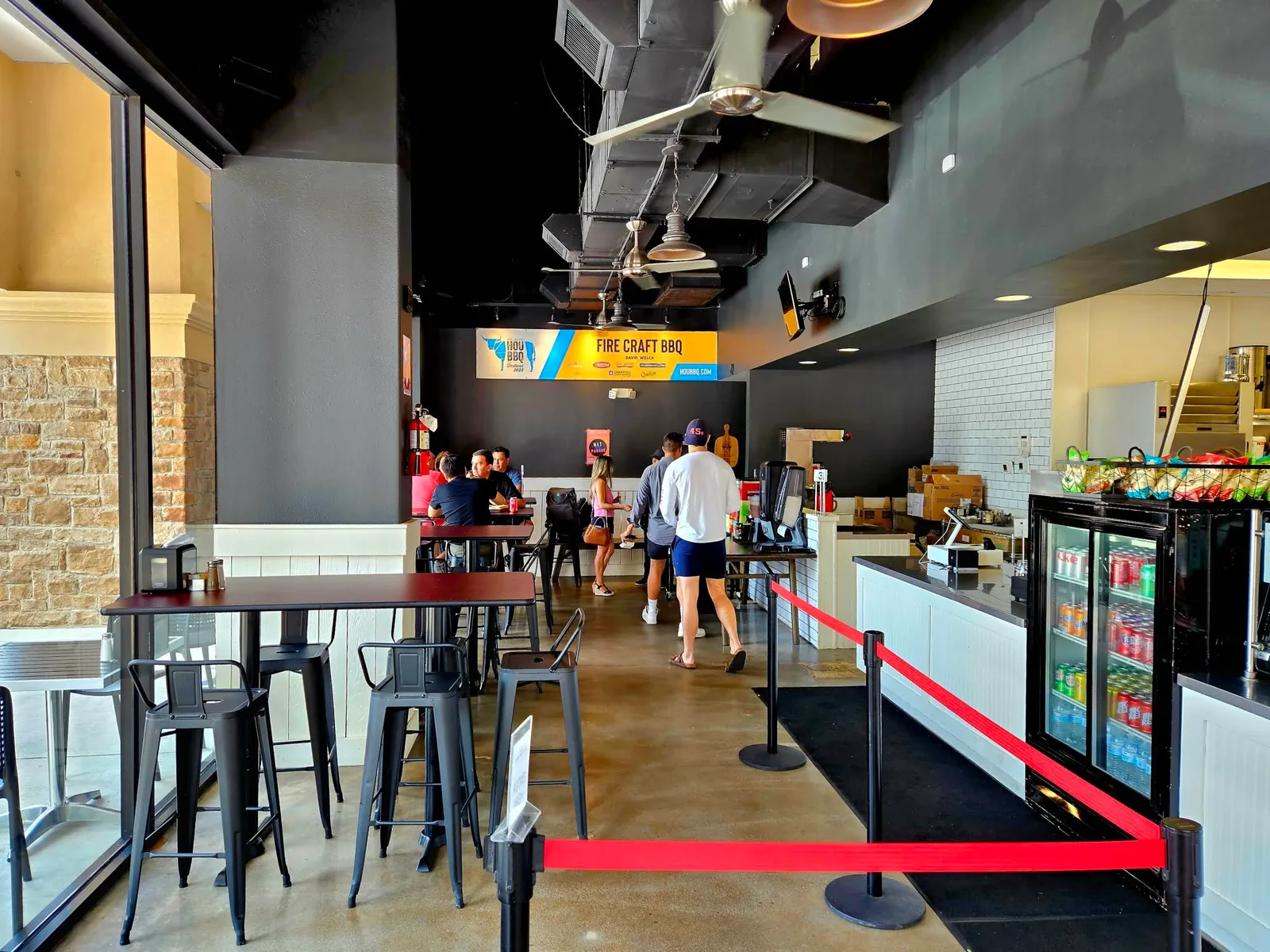 Guests inside Fire Craft with dining tables, the serving counter and the kitchen beyond