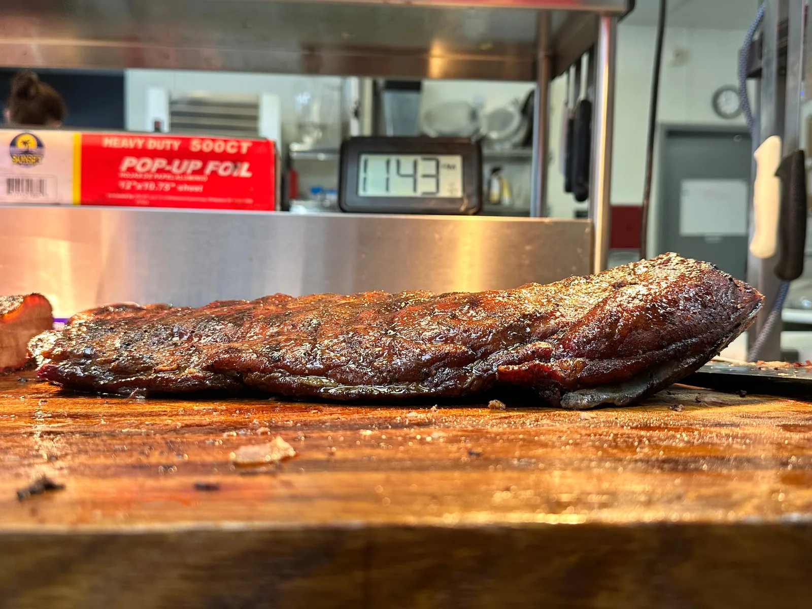 A full rack of smoked ribs resting on a wooden board