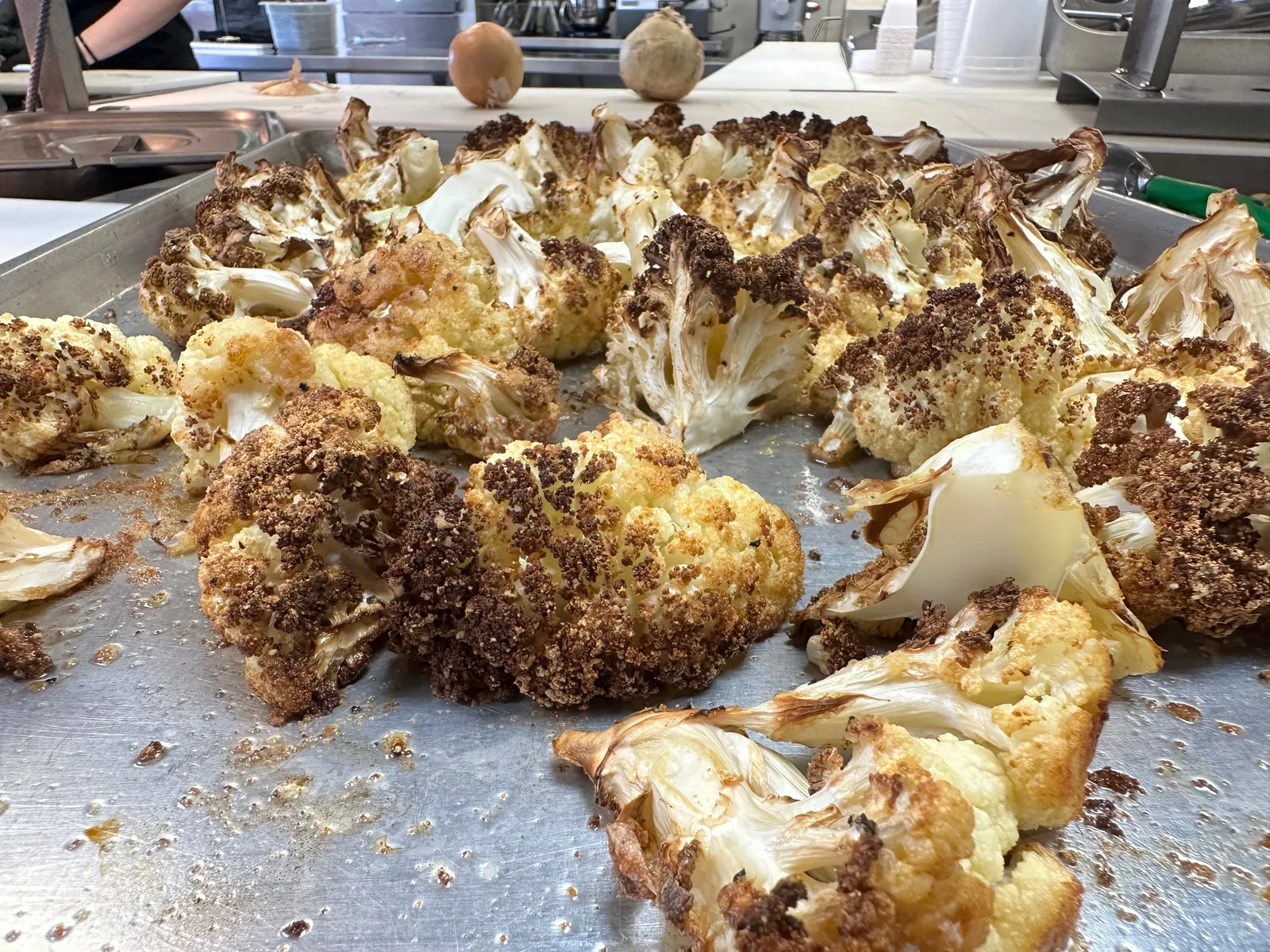 Roasted cauliflower florets spread across a sheet pan