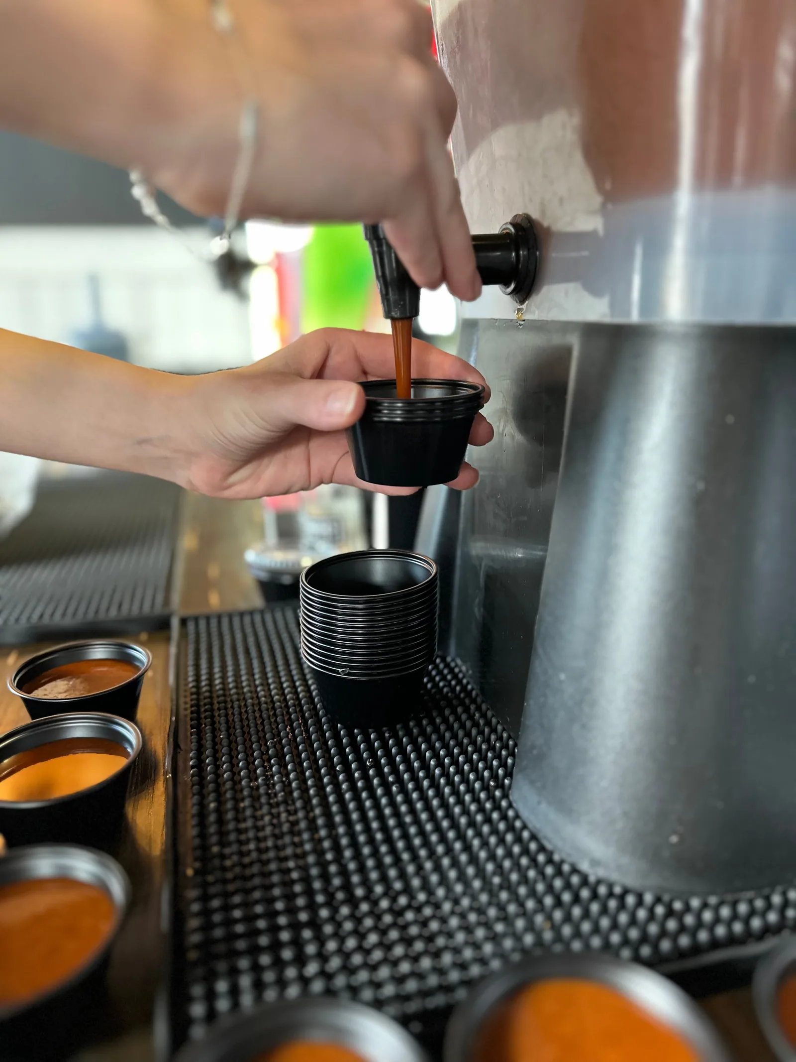 Barbecue sauce being poured into a small serving cup