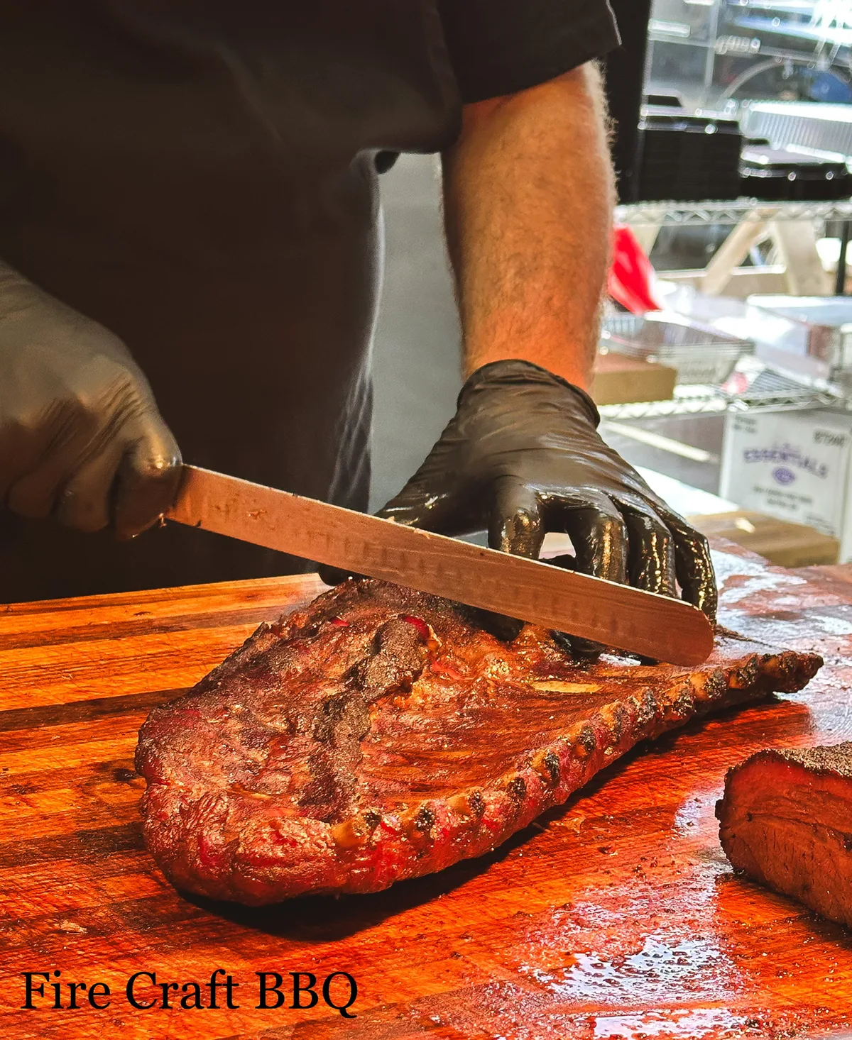 A cook cutting a rack of ribs on a wooden board