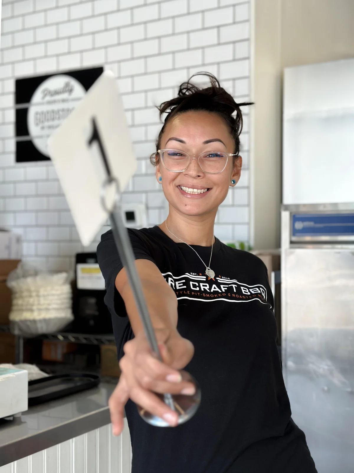 A smiling Fire Craft team member holding a table number